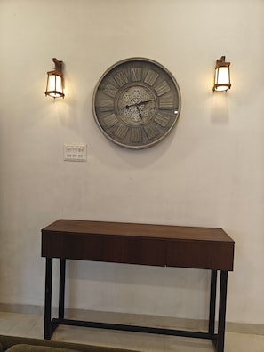 A wall-mounted clock with Roman numerals and two wall-mounted lights.