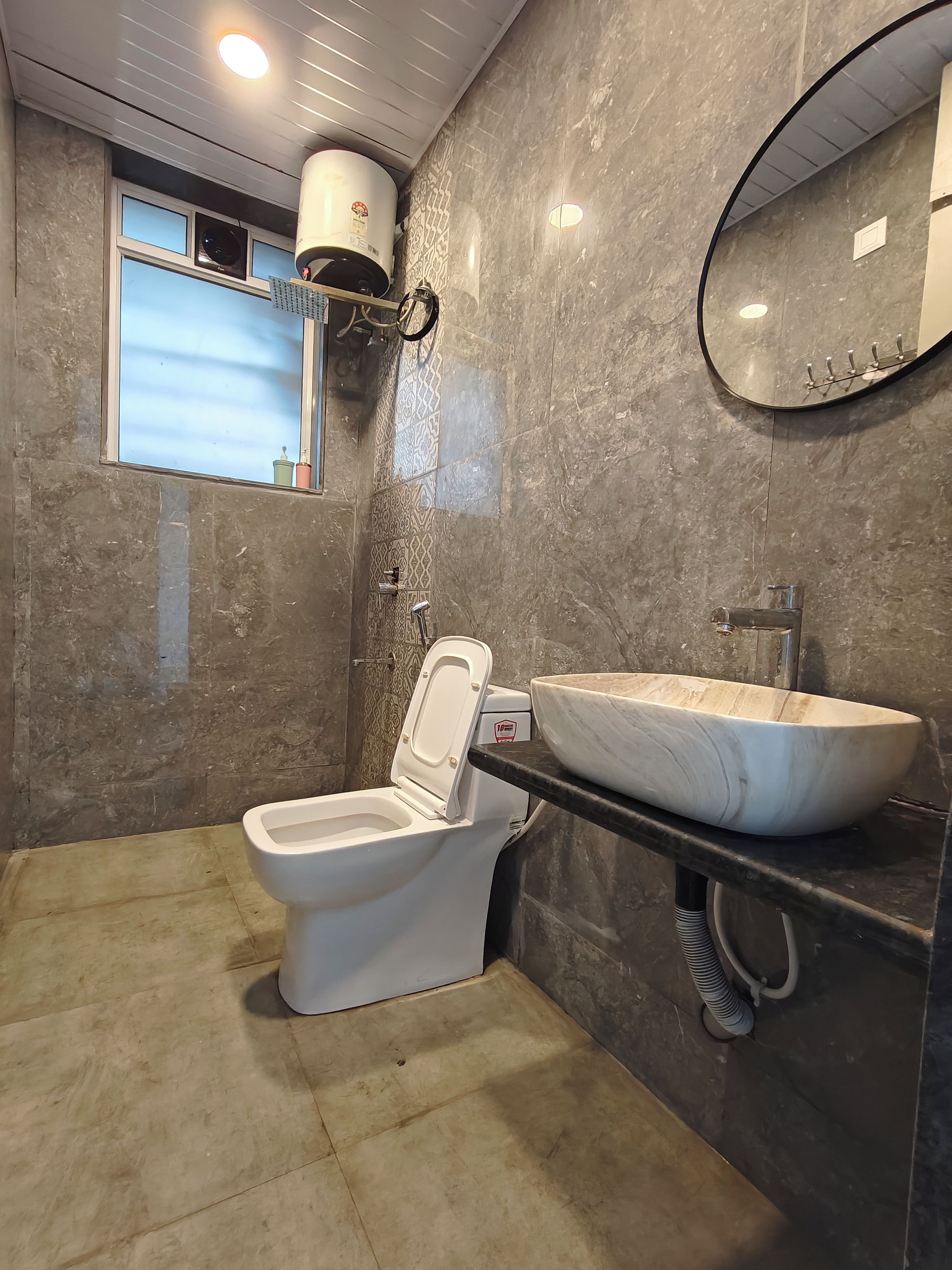 Une salle de bain avec des toilettes, un lavabo, un miroir et une fenêtre.
