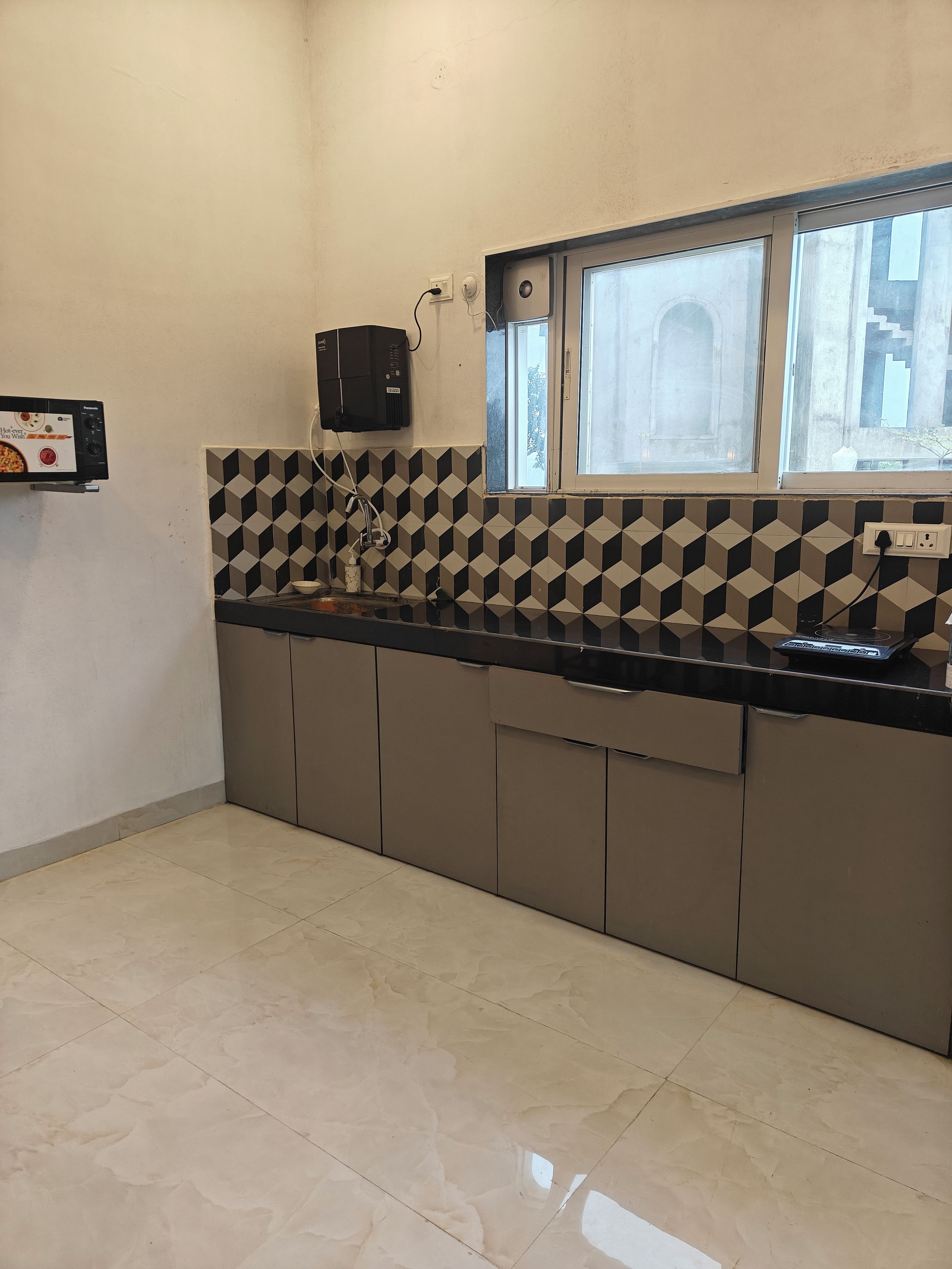 A kitchen with a tiled backsplash, a window, and a microwave.