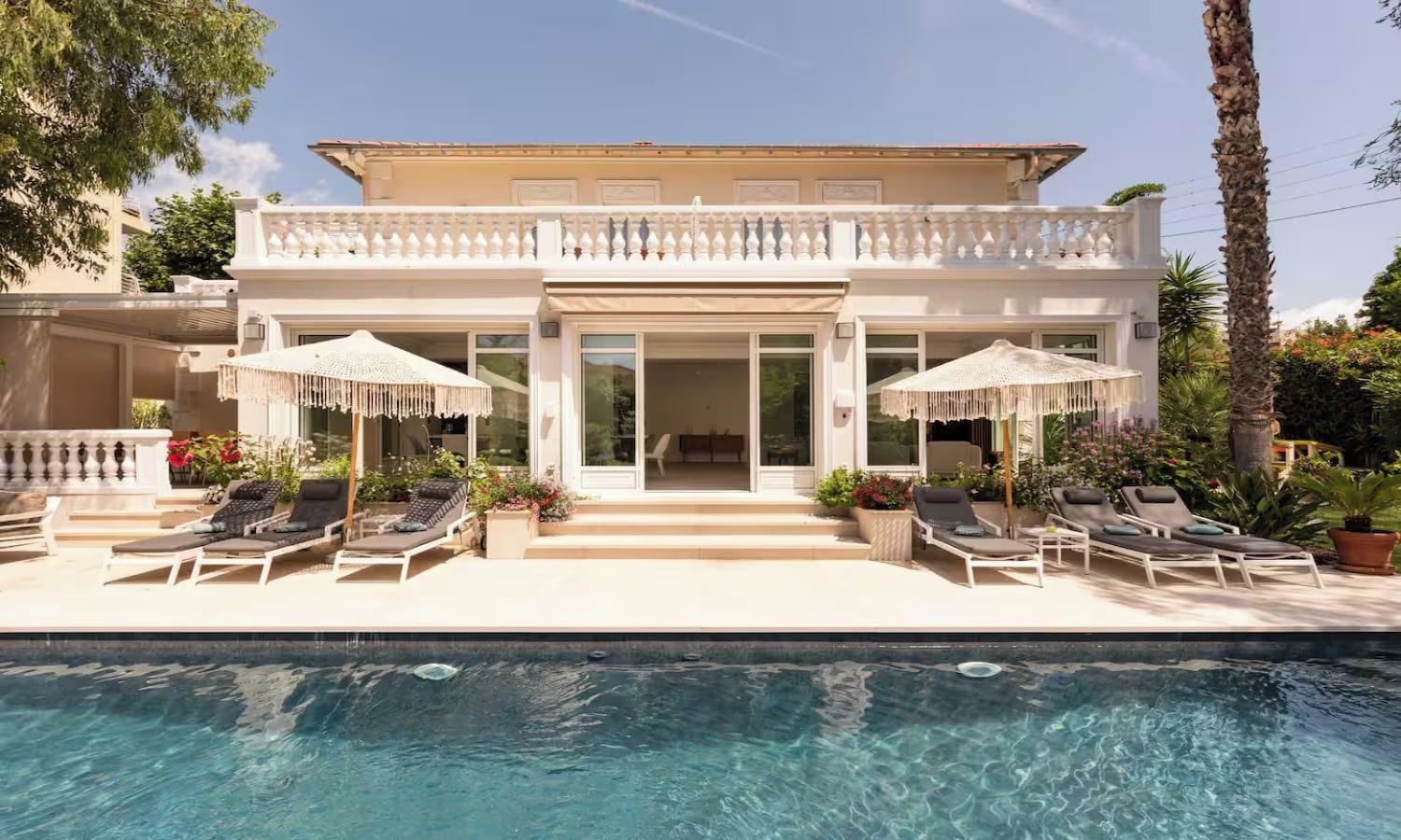 Une maison moderne dotée d’une piscine, d’un espace salon extérieur et d’un patio couvert.