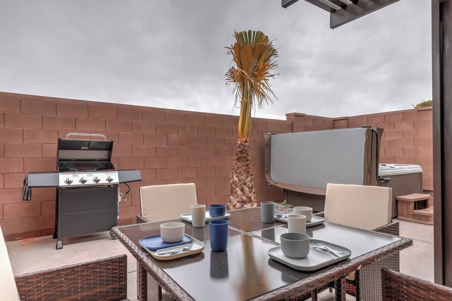 Eine Terrasse im Freien mit Grill, Esstisch, Stühlen und einem großen Bildschirm.