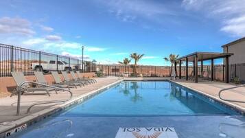 A swimming pool with lounge chairs and a desert landscape in the background.