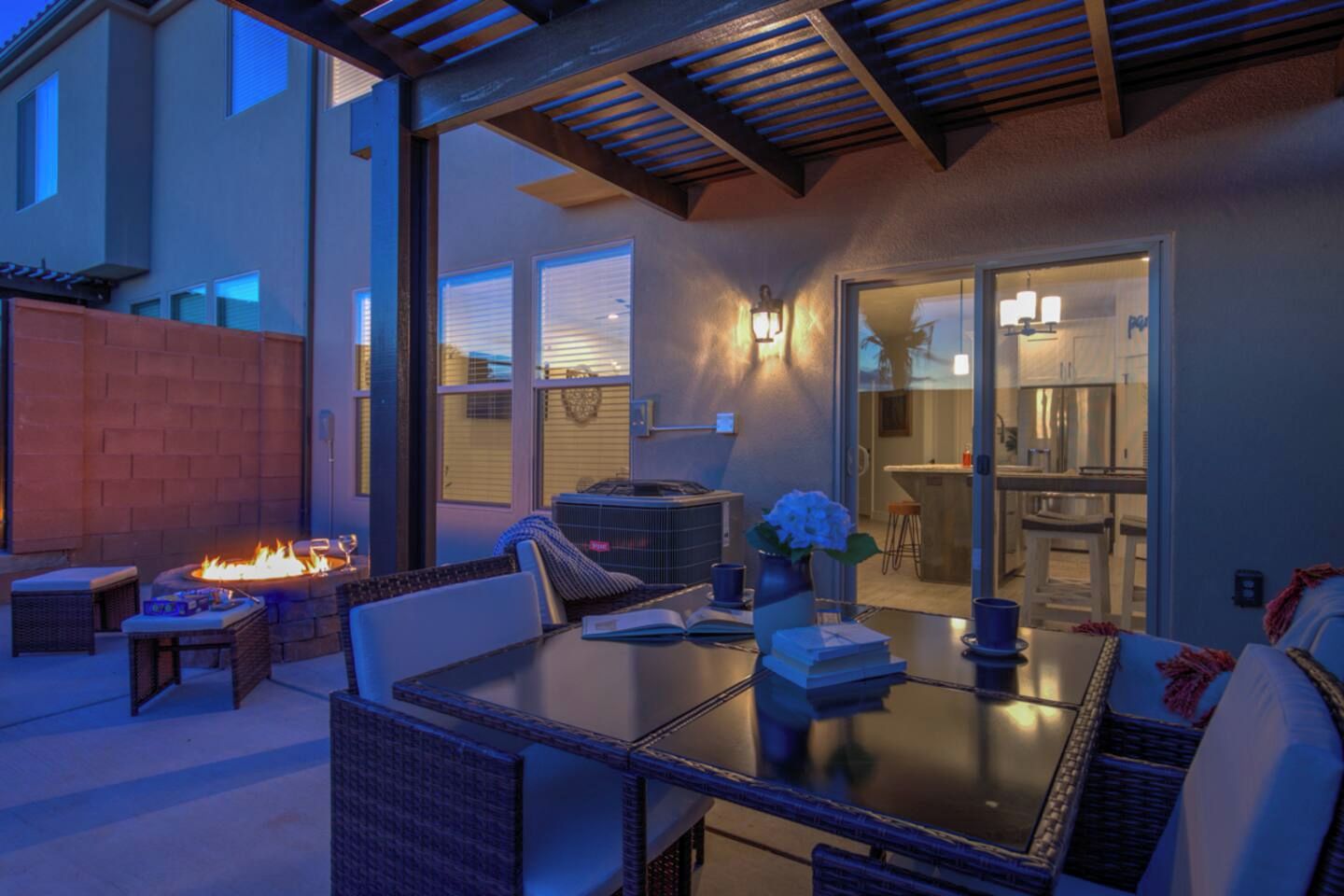 An outdoor patio area with a fire feature, seating, and a view into the house.
