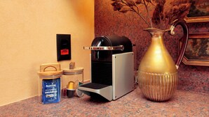 Una cafetera, un recipiente con azúcar orgánica, una jarra de metal y un taburete pequeño sobre una encimera de cocina.