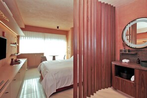 A hotel room with a bed, bedside table, mirror, and a view of the outdoors. - MOBE Studios (São Paulo)
