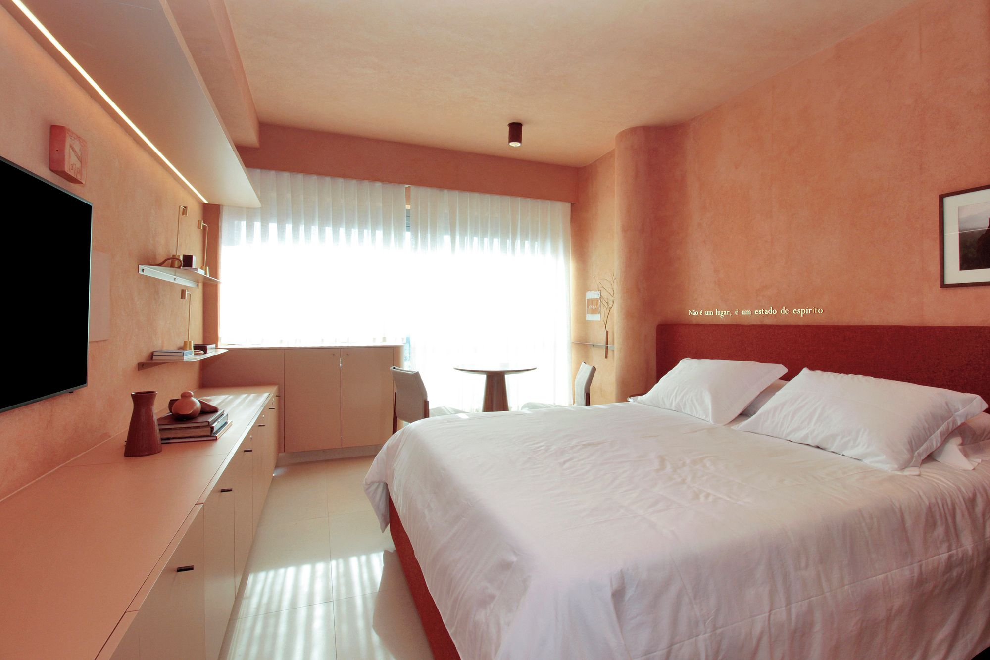 A hotel room with a bed, bedside table, and a TV mounted on the wall.