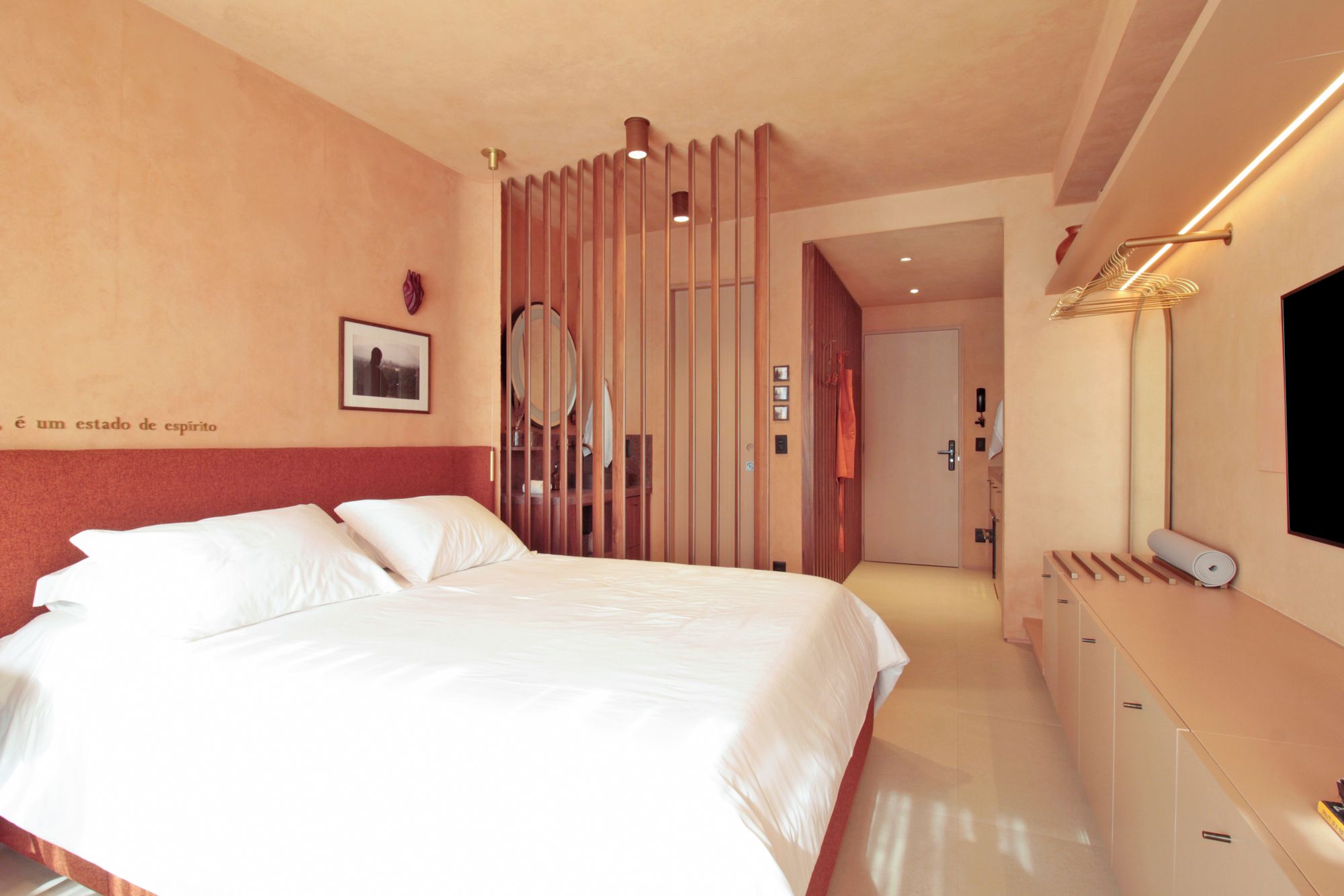 A hotel room with a bed, a dresser, a mirror, and a door leading to another room.