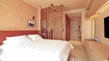 A hotel room with a bed, a dresser, a mirror, and a door leading to another room.