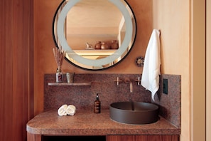 A bathroom with a round mirror, a sink, and a towel rack. - MOBE Studios (São Paulo)