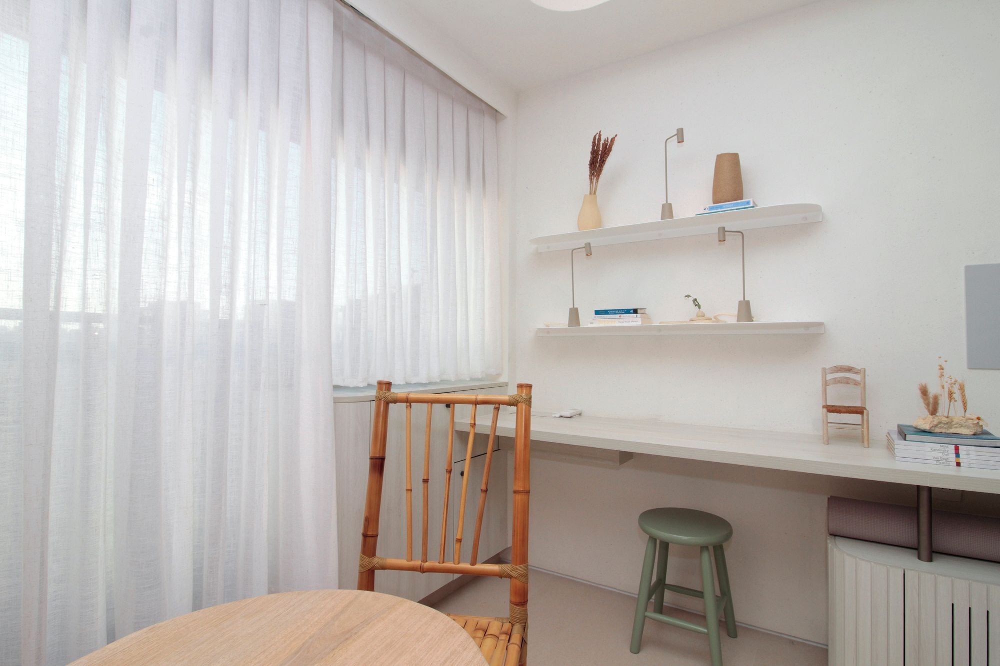 Quarto com mesa de jantar, uma cadeira, um banquinho, radiador e prateleira com objetos decorativos.