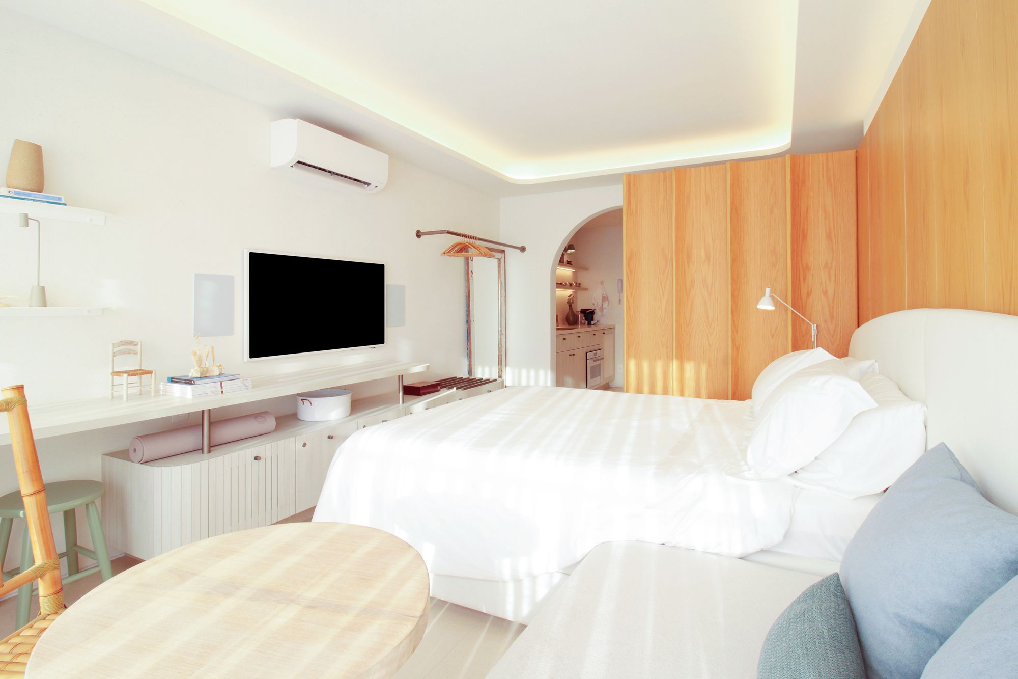 Una camera da letto moderna con un letto grande, una TV a schermo piatto, una scrivania con sedia e un angolo cottura.