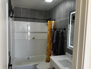 A bathroom with a bathtub, toilet, and a shower area.