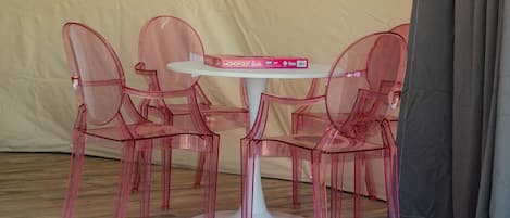 A tent with a table and chairs, a window, and curtains.