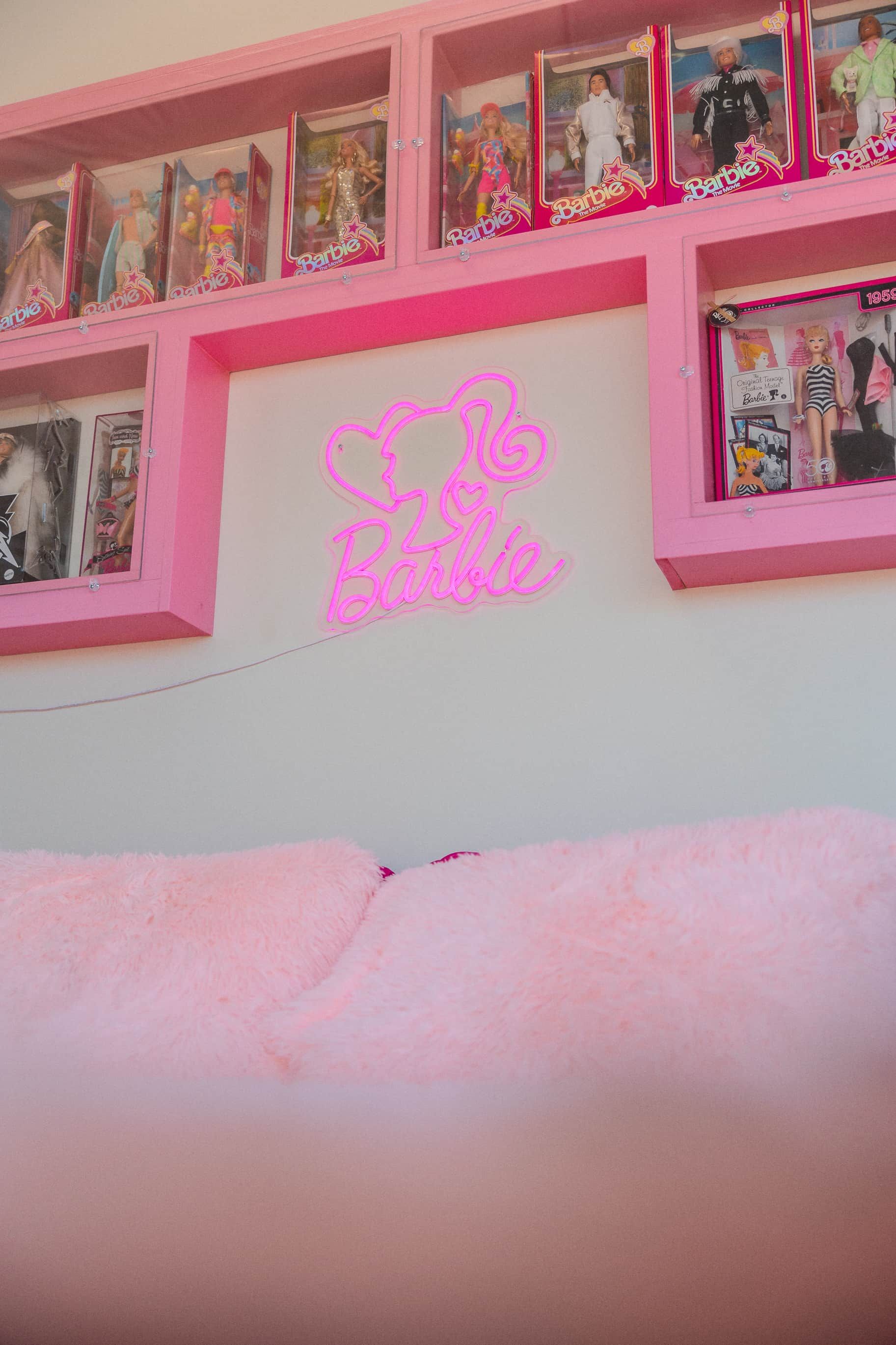 Un letrero de neón rosa con la palabra 'Barbie' y el contorno de un rostro.