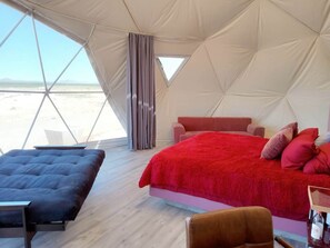 Ein Zelt mit einem Bett, zwei Stühlen und Blick auf den Strand.