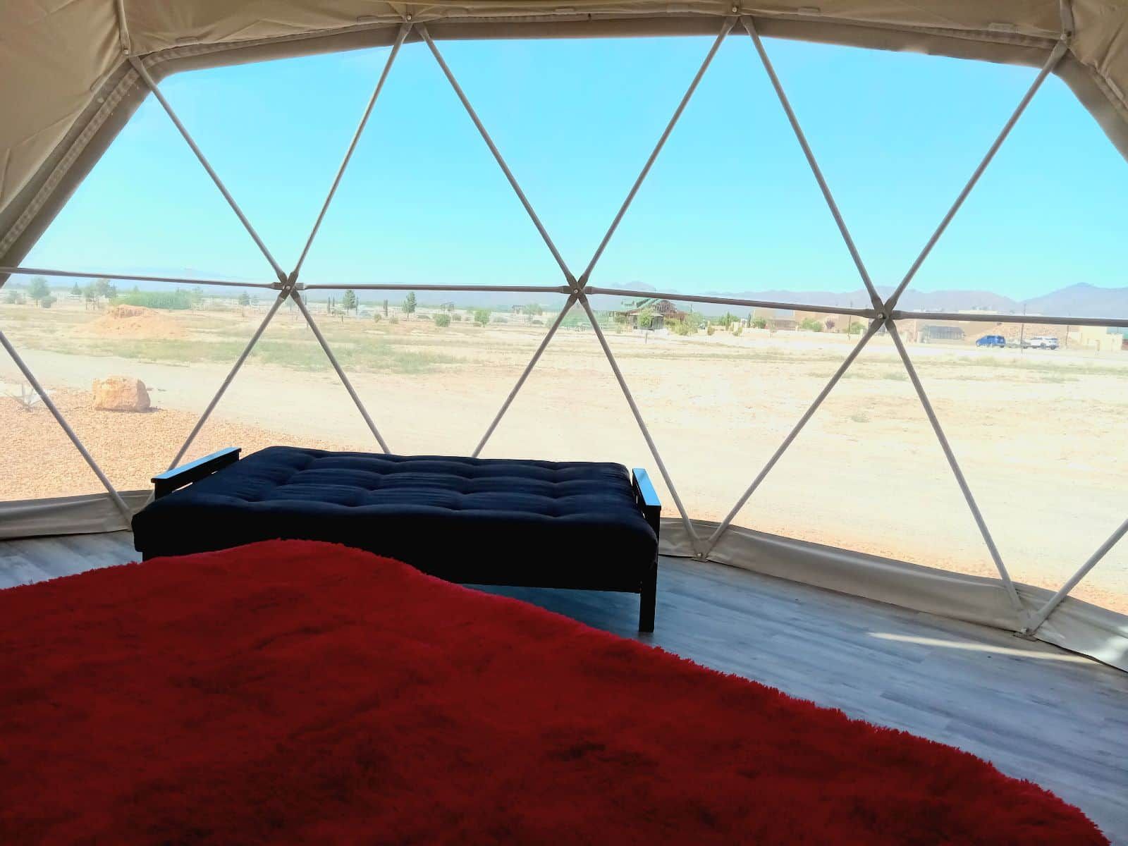 A tent with a bed and a view of a desert landscape.