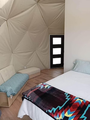 Un dormitorio con una cama, un sofá y una puerta con ventanal.