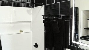 A bathroom with a white bathtub, a large mirror, and a black towel rack. - Cowboy Dome at Tirrito Farm (Cochise County)