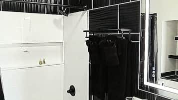 A bathroom with a white bathtub, a large mirror, and a black towel rack.