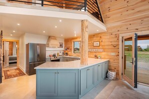A modern kitchen with a central island, built-in appliances, and wooden paneling.