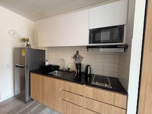 A modern kitchen with a stainless steel refrigerator, a microwave, a sink, and wooden cabinets. - Tranquil 1-bedroom apartment in vibrant Bogotá D.C (Bogotá, D.C.)