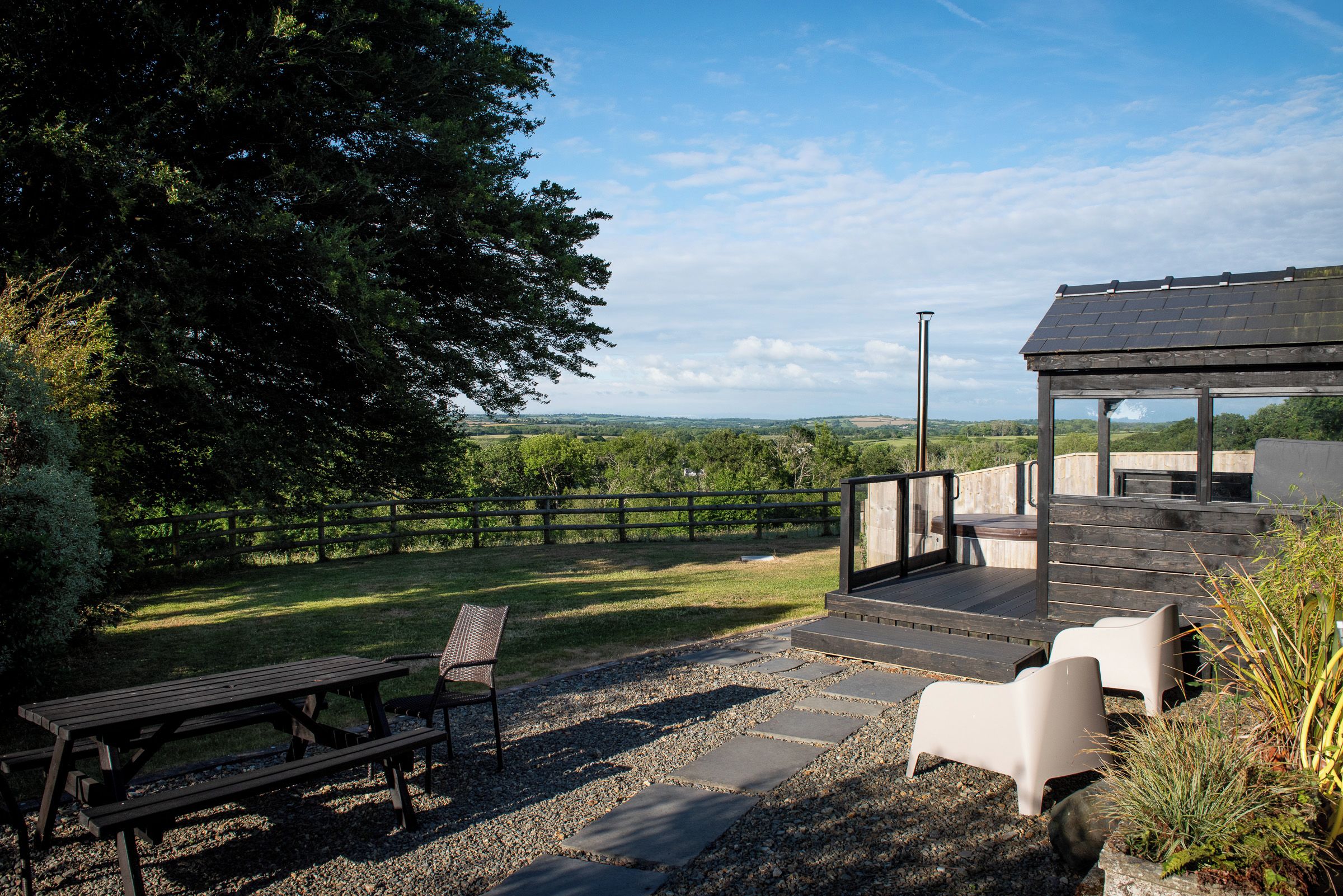 Eine Terrasse im Freien mit Holztisch und -stühlen, einer Pergola mit Dach und Blick ins Grüne.