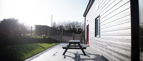 A patio area with a picnic table and a building with horizontal siding.