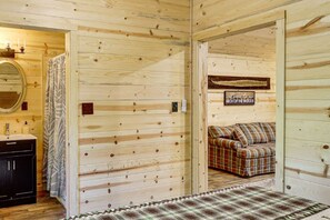 A wooden cabin interior with a bathroom, a bed, and a couch. - Boudreaux Run Cabin Ouachita National Forrest (Langley)