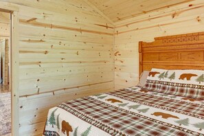 Ein Schlafzimmer einer Holzhütte mit einem Bett, einem Holz-Kopfteil und einer Tür.
