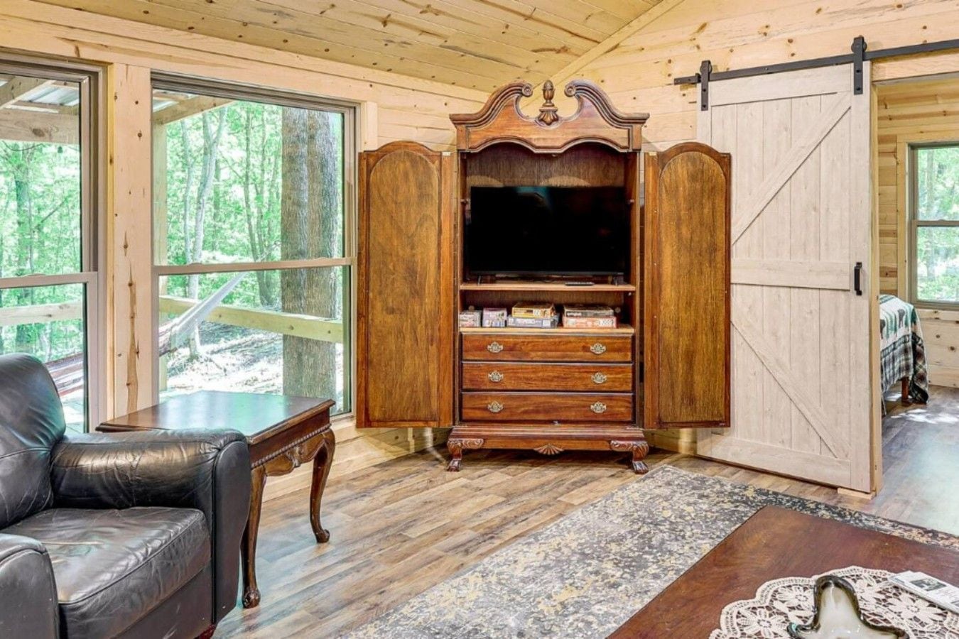 A room with a wooden cabinet, a leather chair, and a large window.
