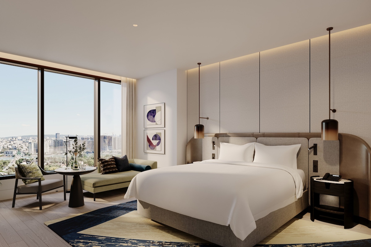 Habitación de hotel moderna con una cama grande, vistas de la ciudad y un paisaje urbano visible a través de la ventana.