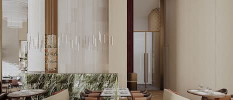 A modern restaurant interior with high ceilings, pendant lighting, and a marble accent wall.