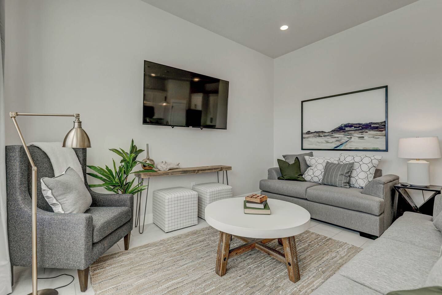 A modern living room with a grey sofa, a round coffee table, and a TV mounted on the wall.