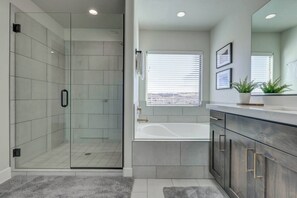 Ein modernes Badezimmer mit einer Duschkabine aus Glas, einer Badewanne und einem Waschtisch mit Spiegel.
