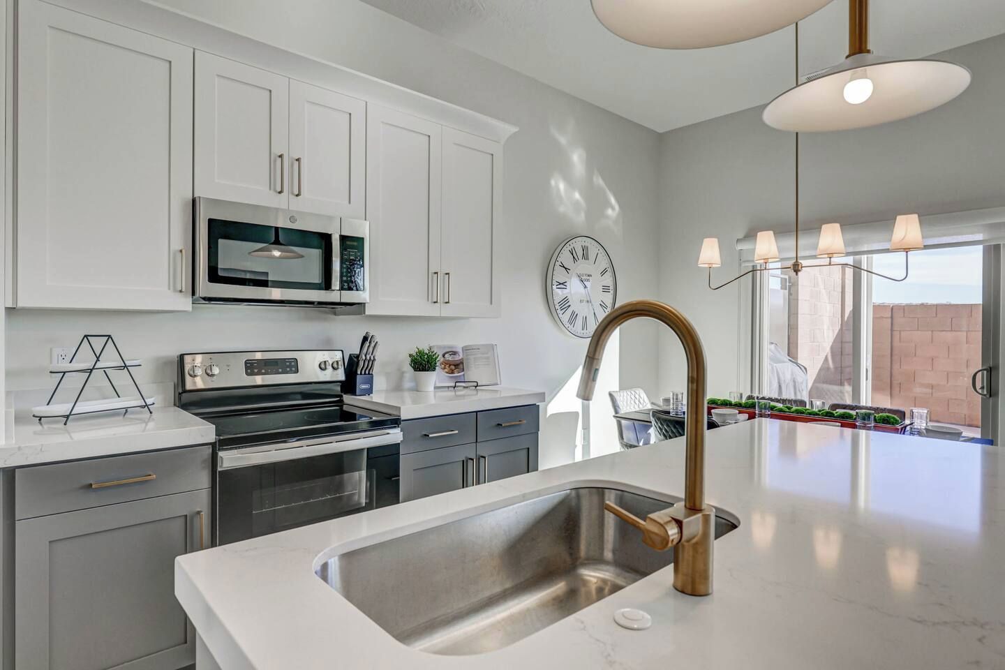 A modern kitchen with white cabinetry, stainless steel appliances, and a large island with a gold faucet.