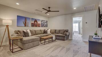 A living room with a sectional sofa, a coffee table, a floor lamp, and artwork on the wall.