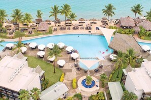 Ein Resort mit großem Schwimmbad, Palmen und Liegebereichen.