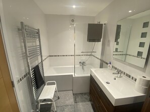 A modern bathroom with a bathtub, a shower, a sink, and a toilet. - Helston 5-bed House, Sleeps 12 With Garden (Helston)