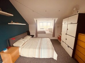 A bedroom with a bed, a desk, a wardrobe, and a window with a view. - Helston 5-bed House, Sleeps 12 With Garden (Helston)