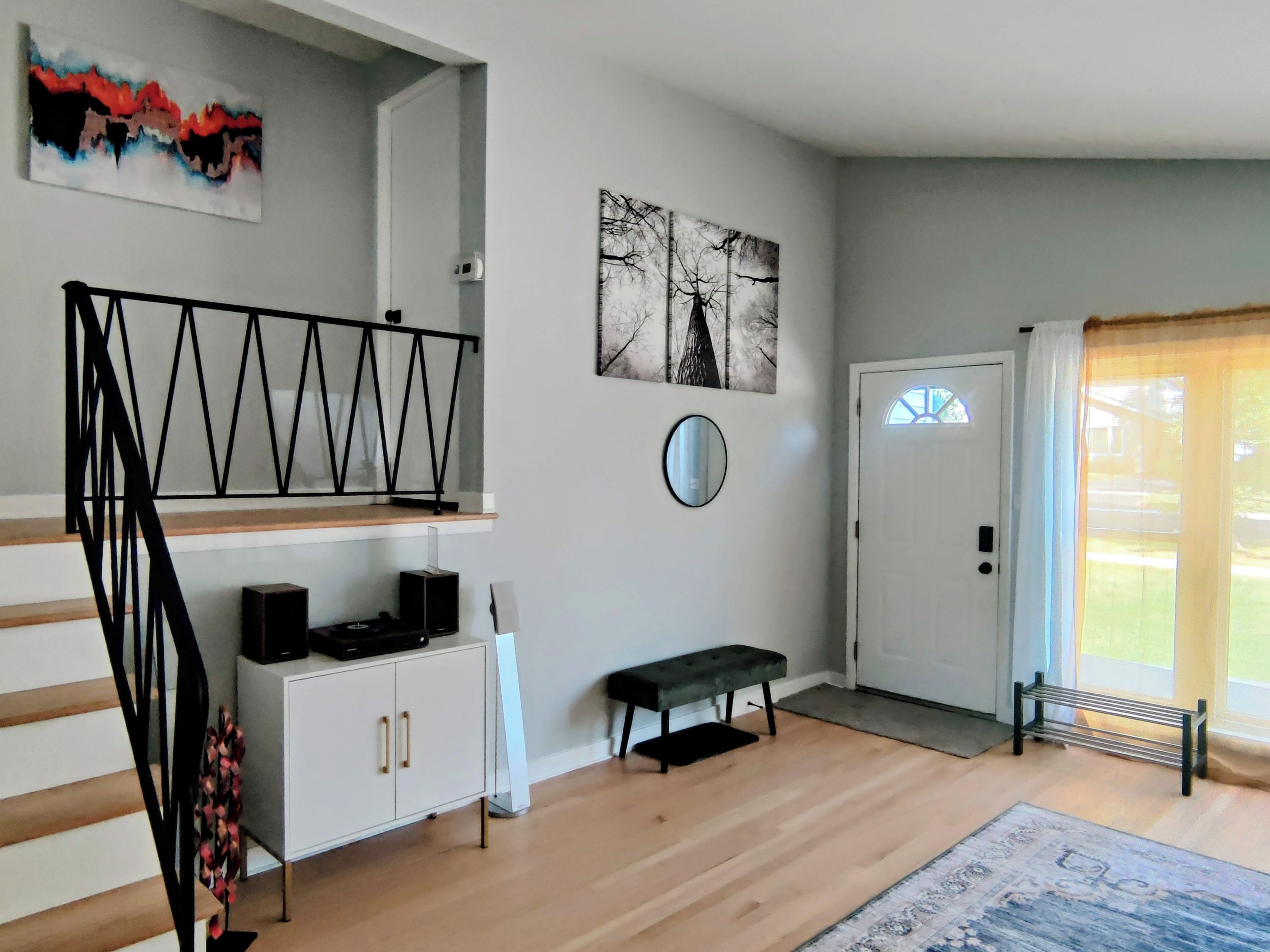 Un intérieur moderne avec un escalier, un banc, une porte et une fenêtre avec des rideaux.