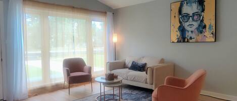 Een woonkamer met een bank, twee fauteuils, een salontafel en een schilderij aan de muur.