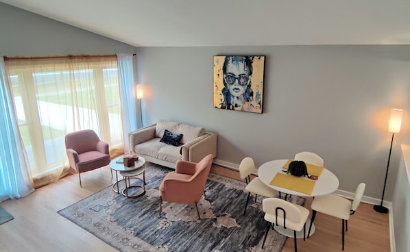 A modern living room with a sofa, chairs, a coffee table, a rug, and a painting on the wall.
