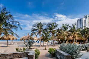 A beach resort with palm trees, thatched umbrellas, and a view of the ocean. - Apartamentos Reserva del Mar - by SOHO (Santa Marta)