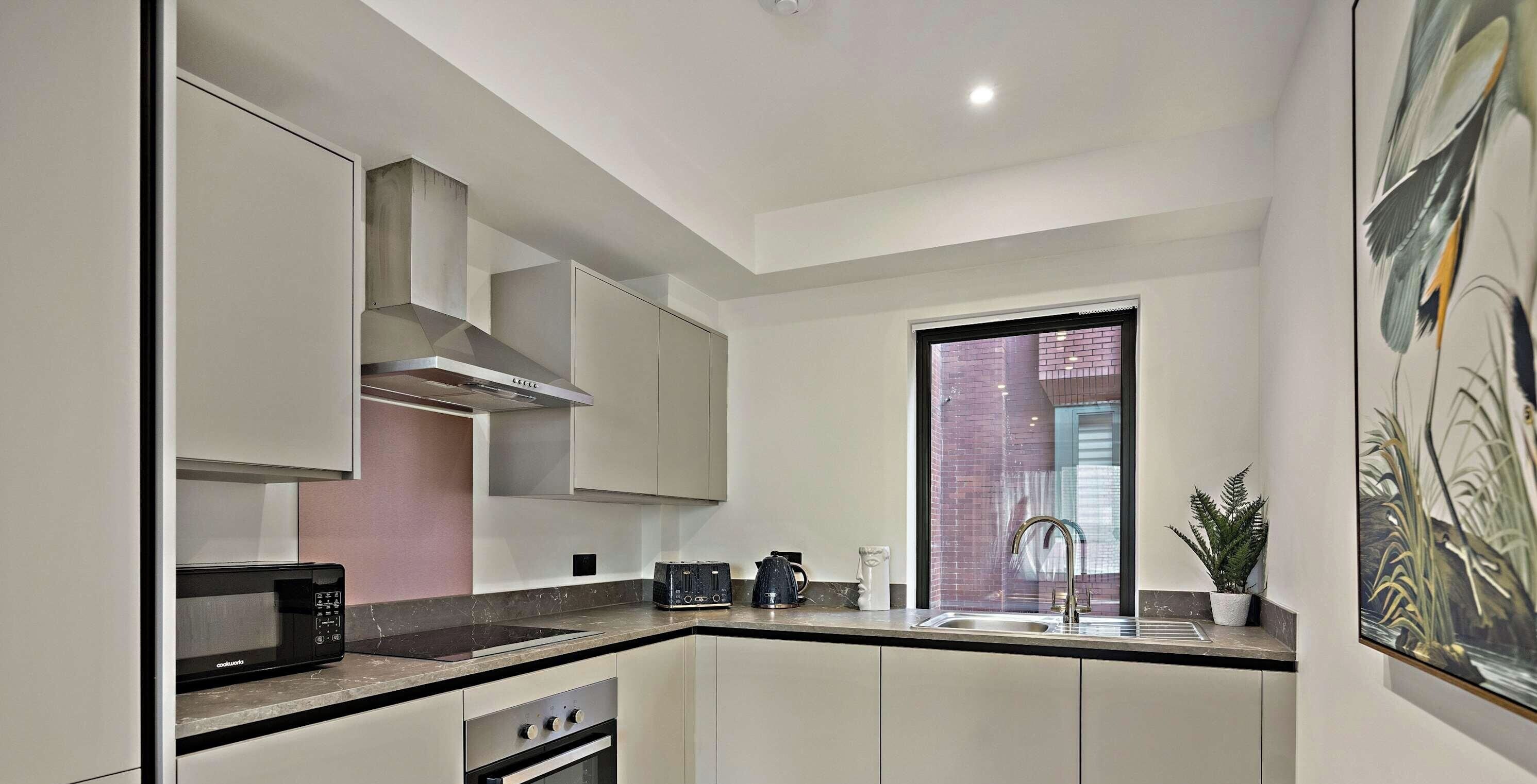 A modern kitchen with a built-in oven, microwave, and a stainless steel range hood.