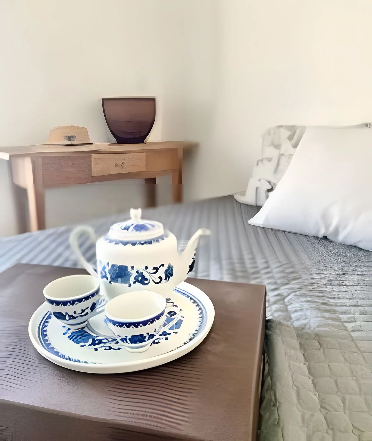A bed with a blue and white patterned tea set on a wooden table.