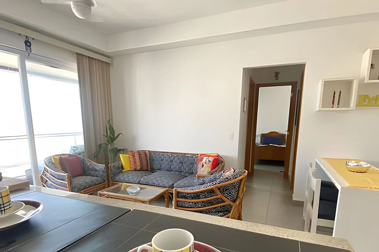 A modern living room with a sofa, a dining table, and a kitchen area.