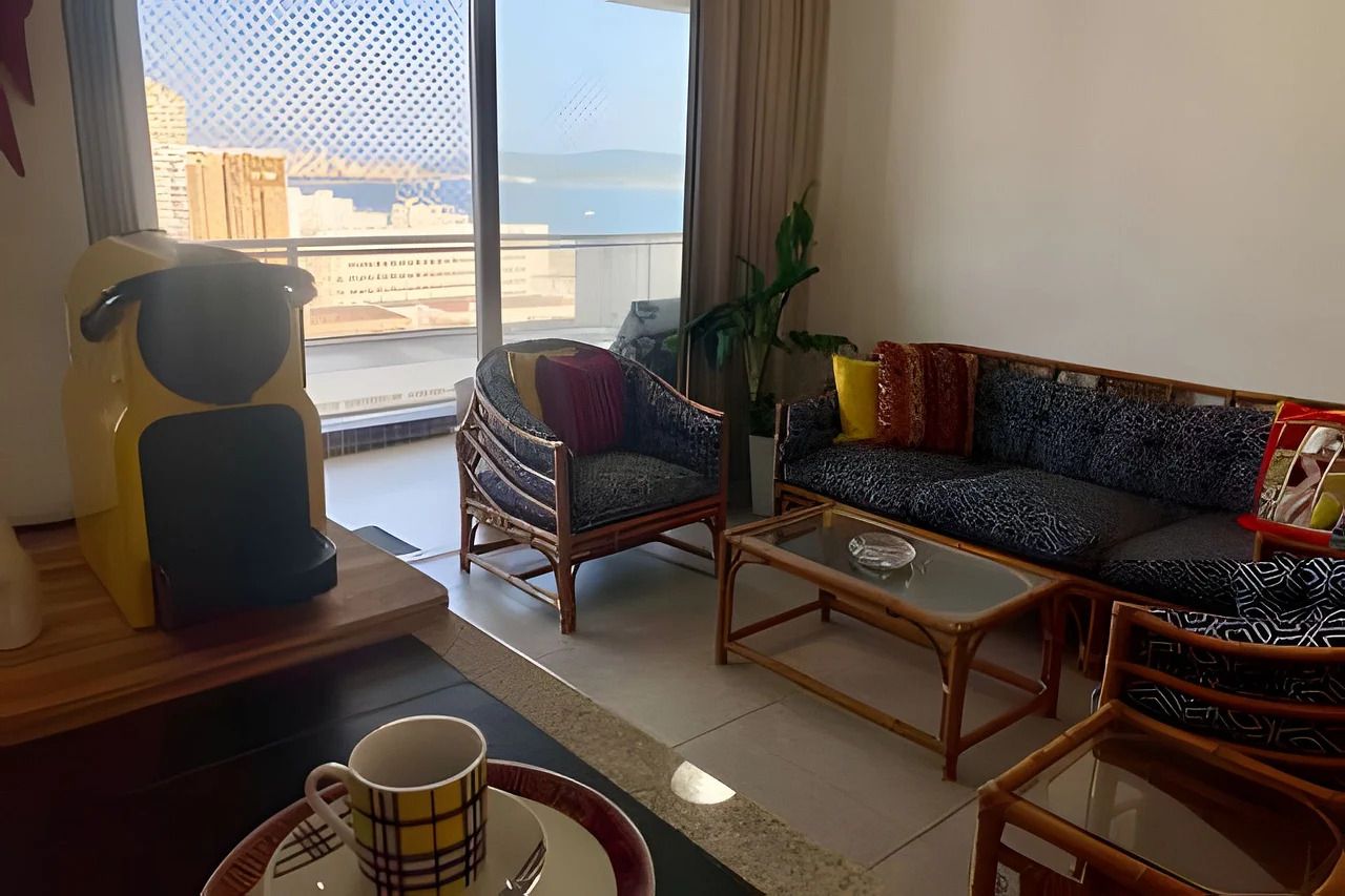 Ein Wohnzimmer mit einer Couch, Sesseln, einem Couchtisch und Blick auf die Stadt durch große Fenster.