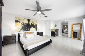 Una camera da letto moderna con un letto grande, una ventola a soffitto, un quadro e uno specchio.