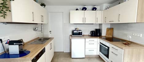 A modern kitchen with white cabinets, a dishwasher, a microwave, and a coffee maker.