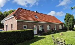 A two-story brick house with a red-tiled roof, a small front porch, and a well-maintained lawn. - Norderland Vacation Home (Norden)